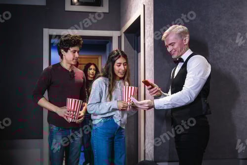 Preview: Usher checking tickets and smartphone at movie theater entrance