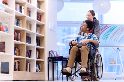 Preview: Boy with Disability Choosing Books in Library with Girl Assisting