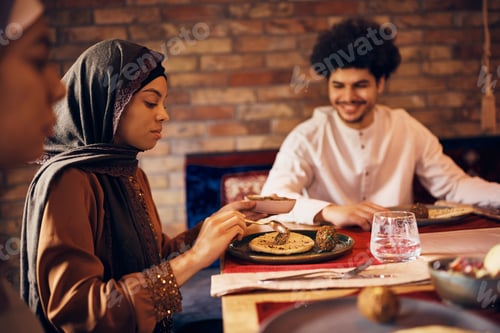 Preview: Young Muslim woman and her family having Iftar meal at home during Ramadan.