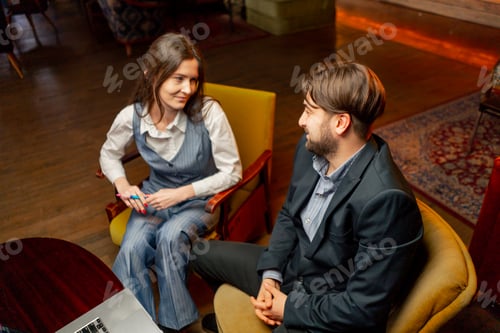 Preview: recreation area sitting on yellow chairs a businessman makes deal with a female director discussion