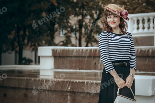 Preview: A young woman fashionably dressed in a vintage straw hat walks in an autumn park