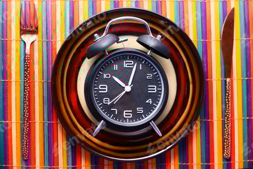 Preview: Alarm clock on plate on wooden table, top view.