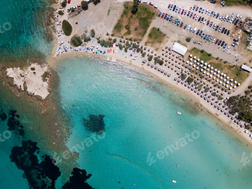 Preview: Aerial view of a vibrant beach in Sithonia, Greece, with colorful umbrellas, sunbeds, and beachgoers