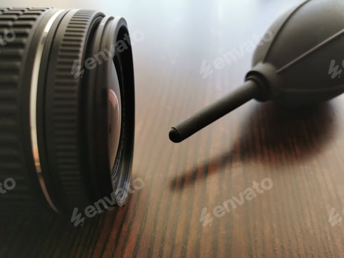 Preview: Camera and air blower on wood table. Photo can be used for the concept of how to clean a camera lens