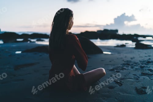 Preview: Young woman meditating on dark seashoer