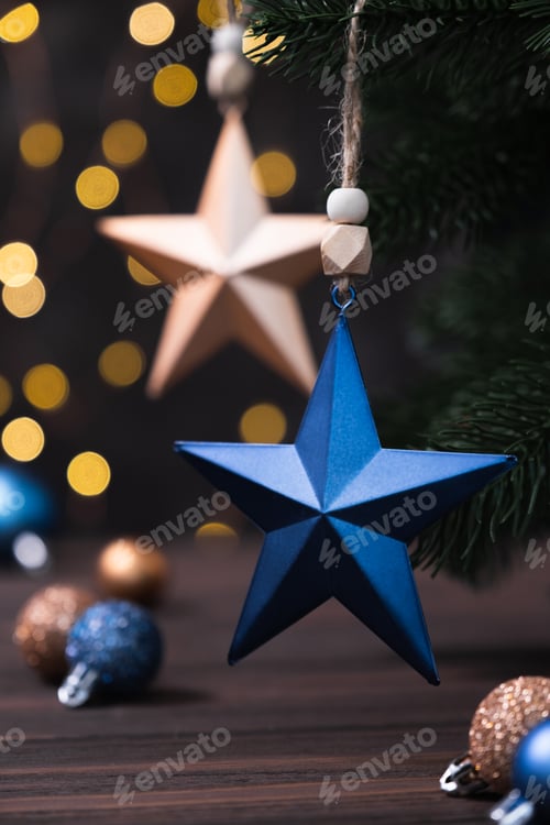 Preview: Christmas composition with blue and beige stars, fir tree branches on blurred brown background.