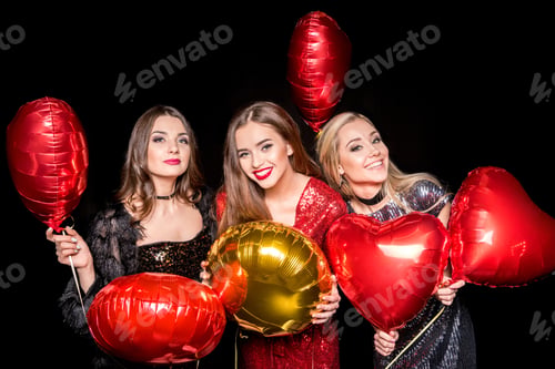 Vista previa: Gorgeous young women posing with shiny balloons and smiling at camera isolated on black