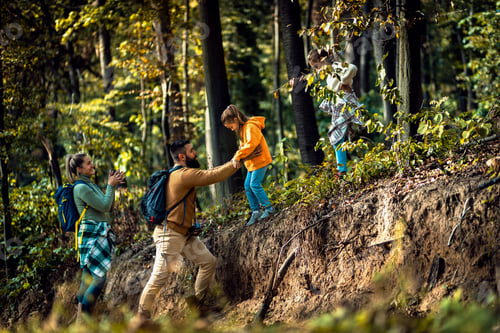 Preview: Smiling family of four enjoying hiking in trough forest.