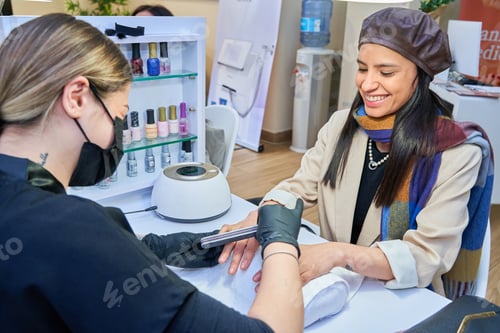 Preview: Doing manicure in salon. Female manicurist working on client nails in professional salon.