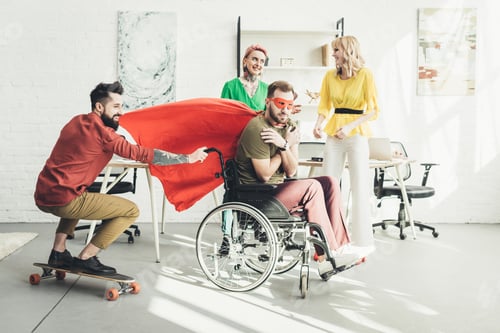 Preview: disabled businessman in superhero costume with colleague on skateboard and businesswomen behind in