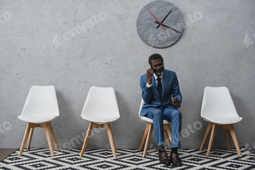 Preview: Angry Middle aged businessman talking by smartphone in a waiting room