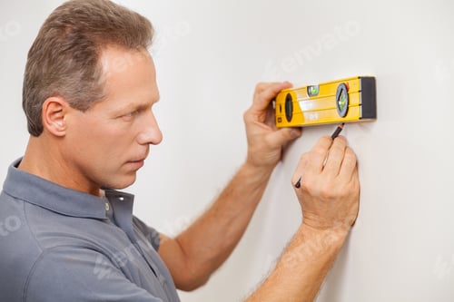 Preview: Taking wall measurements. Side view of confident mature man taking measurements of the wall