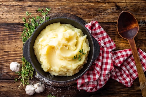 Preview: Mashed potatoes, boiled puree in cast iron pot on dark wooden rustic background, top view