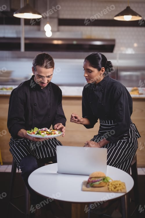 Preview: Young wait staff discussing over food while sitting at coffee shop