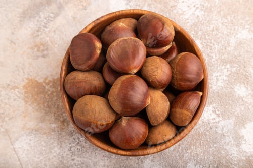 Preview: wooden bowl with raw edible Сhestnuts on brown concrete, top view, flat lay, close up, minimalism