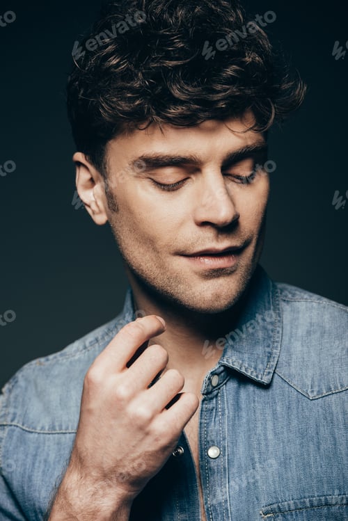 Preview: handsome stylish man posing in jeans shirt isolated on dark grey