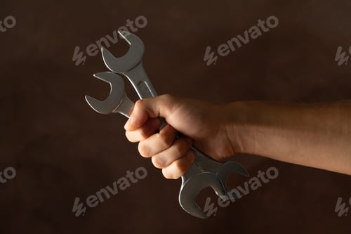 Preview: Male hand holds wrenches on brown background