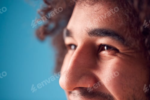 Preview: Close Up On Eyes Of Smiling Young Man Against Blue Background In Studio