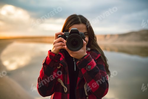 Preview: Young woman taking picture with camera on the beach