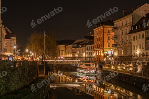 Preview: Cityscape with illuminated buildings on both sides of the river at night in Ljubljana
