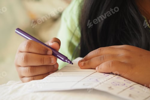 Preview: Child writing notes with a purple pen on a cozy surface