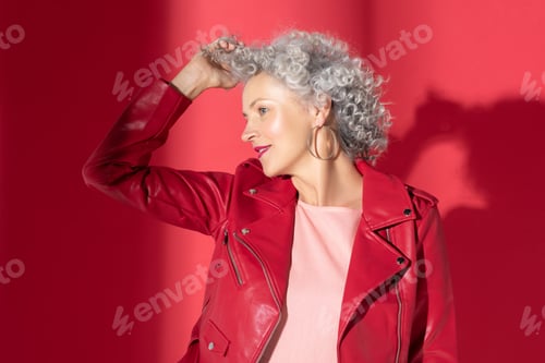 Preview: Curly grey-haired woman wearing red jacket feeling delightful