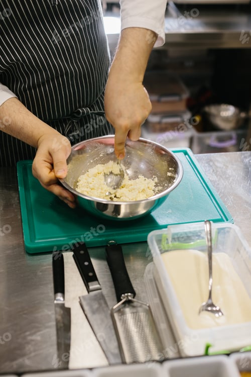 Preview: Close up. A male cook prepares pancake batter in a metal bowl in the kitchen of a restaurant.