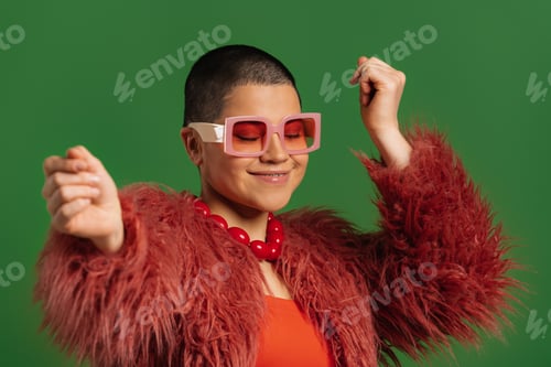 Preview: Fashionable young short hair woman in trendy clothes dancing against green background