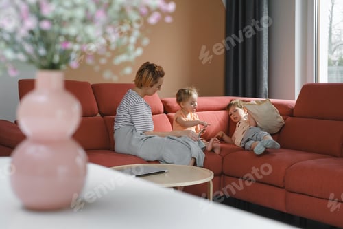 Preview: Mother reading book with two children on sofa