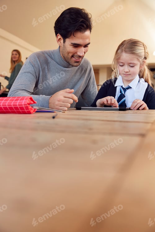 Preview: Father Helping Daughter Using Digital Tablet Wearing School Uniform With Homework At Table