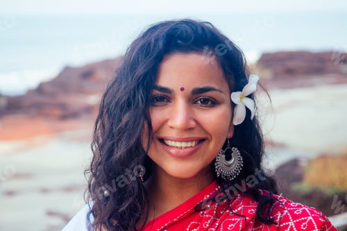 Preview: Indian female fashion model white-toothed smile with flower in her curly hair