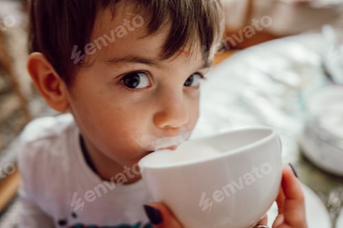 Preview: Cute baby boy drinking yogurt from cup