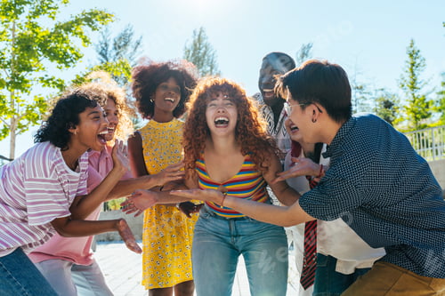 Preview: Multiethnic group of young friends meeting and having fun outdoors