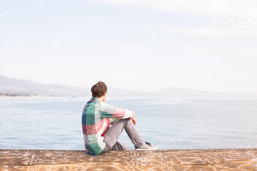 Preview: Young man looking at view across the water