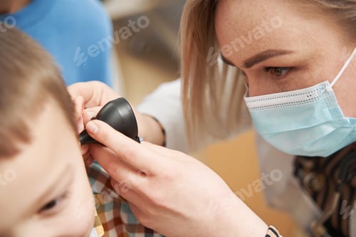 Preview: Pediatrician examining child ear with otoscope in clinic