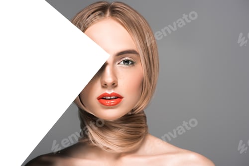 Preview: attractive young woman with long hair around neck and blank card looking at camera isolated on grey