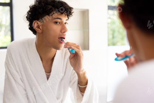 Preview: Brushing teeth in bathroom, young young man in bathrobe looking in mirror