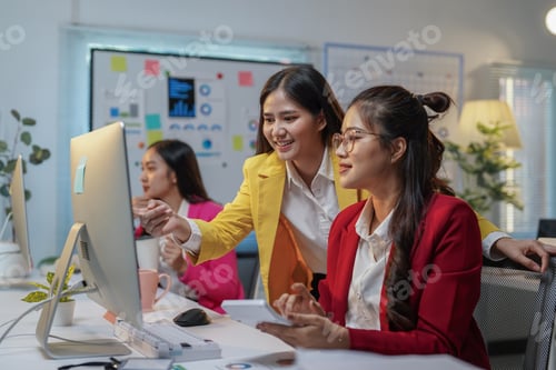 Preview: Two asian businesswomen are analyzing financial data on a computer and discussing a project together