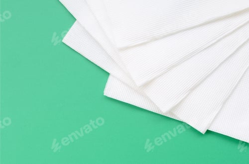 Preview: Several white paper napkins lie on a plastic green background