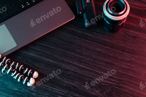 Preview: A workspace with laptop, lens and tripod on a wood desk.