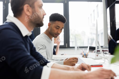 Preview: Two male coworkers working at computer in an office