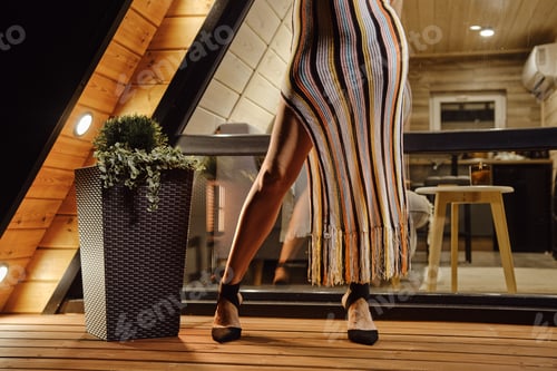 Preview: Female legs in high heel shoes and knit beach dress on terrace