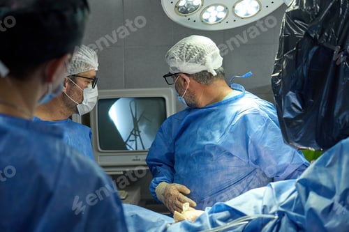 Preview: Surgeons looking at monitor and discussing procedure in operating room