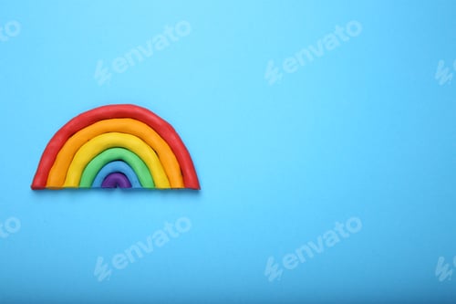 Preview: Beautiful rainbow made of plasticine on light blue background, top view. Space for text