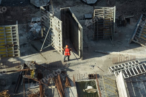 Preview: Construction worker in high visibility clothing operating tower crane lifting panel from formwork