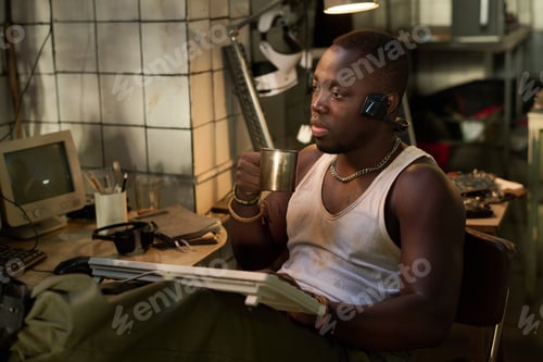 Preview: Black Man Drinking Tea While Working On Old Computer