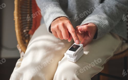 Preview: A woman using digital fingertip pulse oximeter device to measure oxygen and blood pulse rate