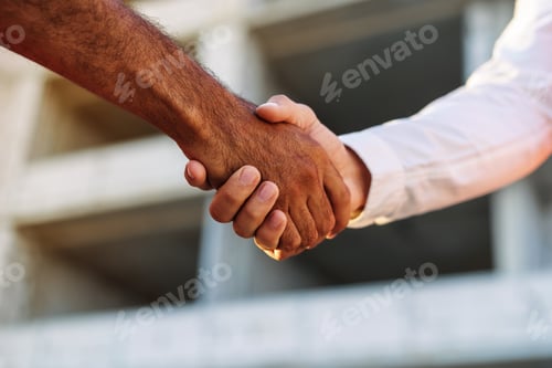 Preview: Close up of two men shaking hands against construction site
