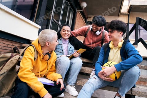 Preview: Group of happy young colleagues talking and having fun together outdoors on college campus.