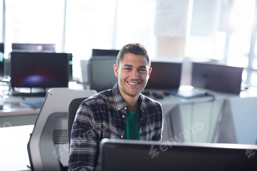 Preview: Young man working on desktop computer in modern office, smiling at camera with computer monitor